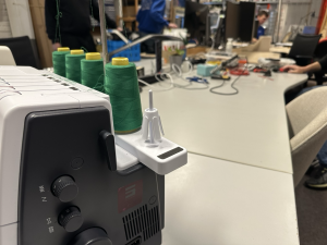 Naaimachine met vier klossen groene garen erop.